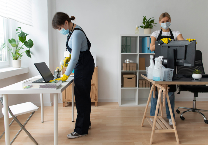 Office cleaner sanitising desks and workstations in Wollongong
